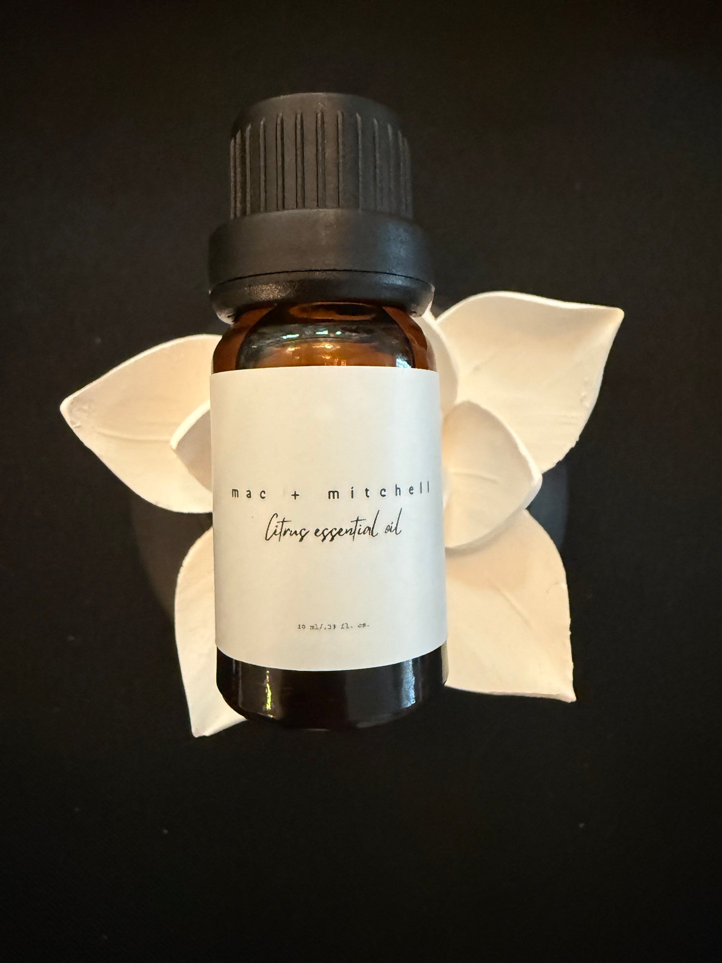 mac + mitchell essential oil bottle with dried botanical flowers