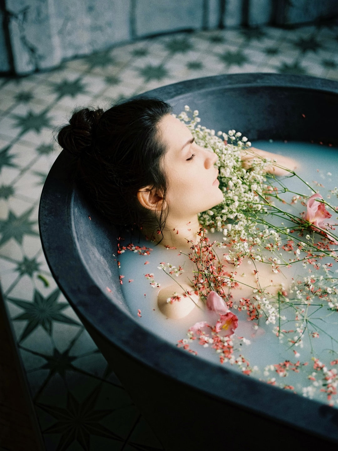 woman soaking in mac + mitchell lux milk bath with flowers side view