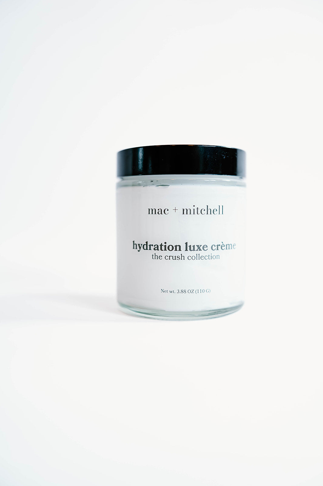 glass jar of hydration luxe crème with a black lid, filled with white cream.