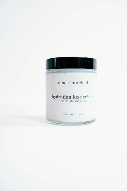 glass jar of hydration luxe crème with a black lid, filled with white cream.