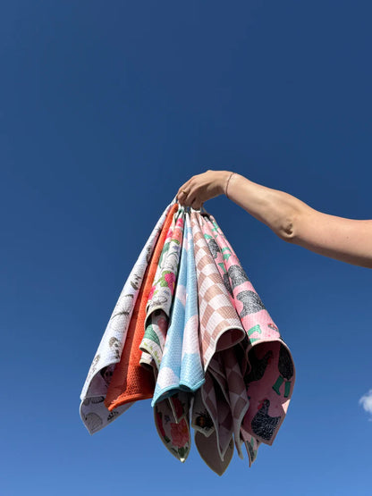 woman holding multiple crae microfiber hand towels against blue sky by mac + mitchell