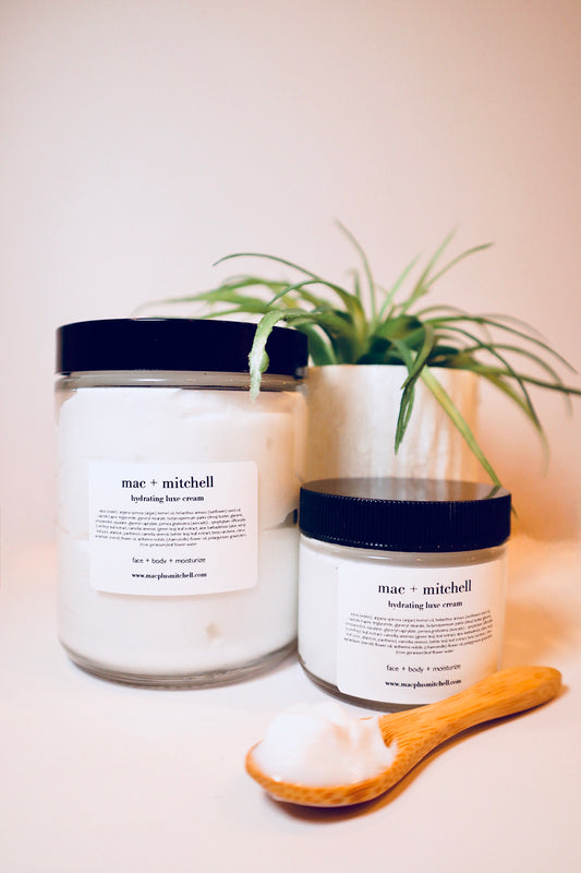 mac + mitchell hydration luxe creme in two glass jar sizes with wooden spoon and plant