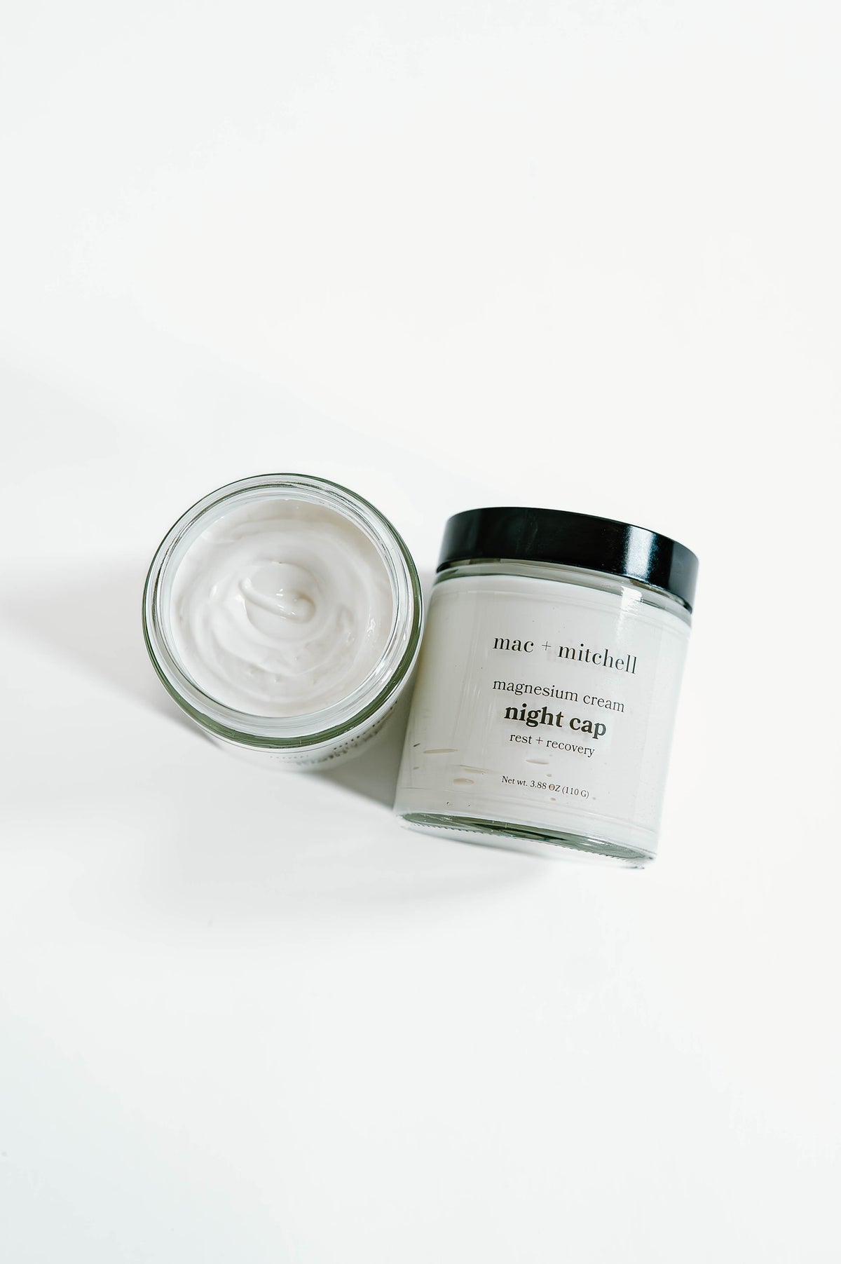 open jar of night cap magnesium cream showing the whipped white texture, beside a closed jar.