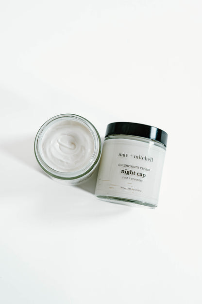 open jar of night cap magnesium cream showing the whipped white texture, beside a closed jar.