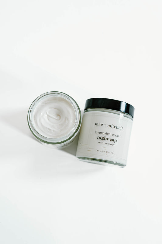 open jar of night cap magnesium cream showing the whipped white texture, beside a closed jar.