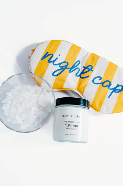 jar of night cap magnesium cream beside magnesium flakes and a striped night cap sleep mask.