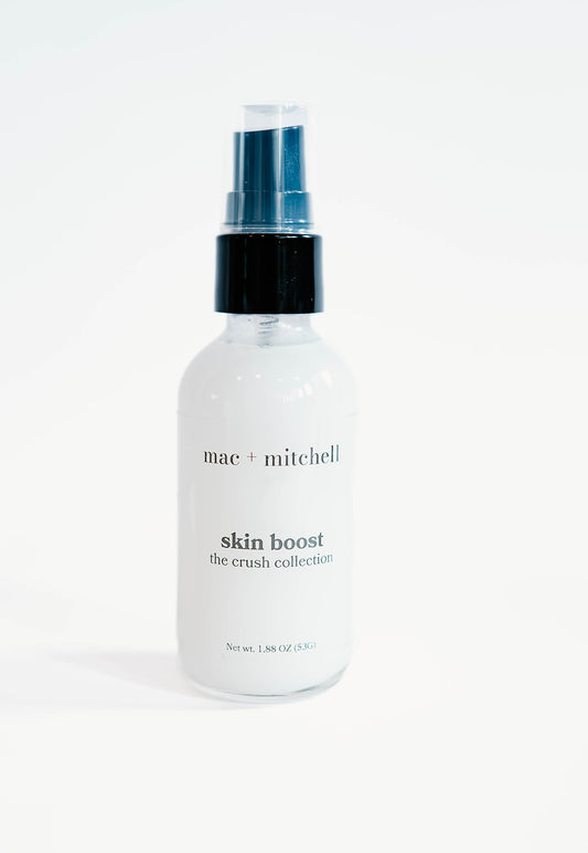clear glass bottle of skin boost with a black pump, filled with white serum.